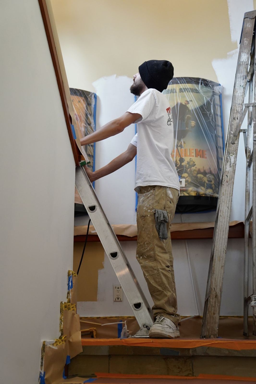 A painter setting a ladder to reach a high wall