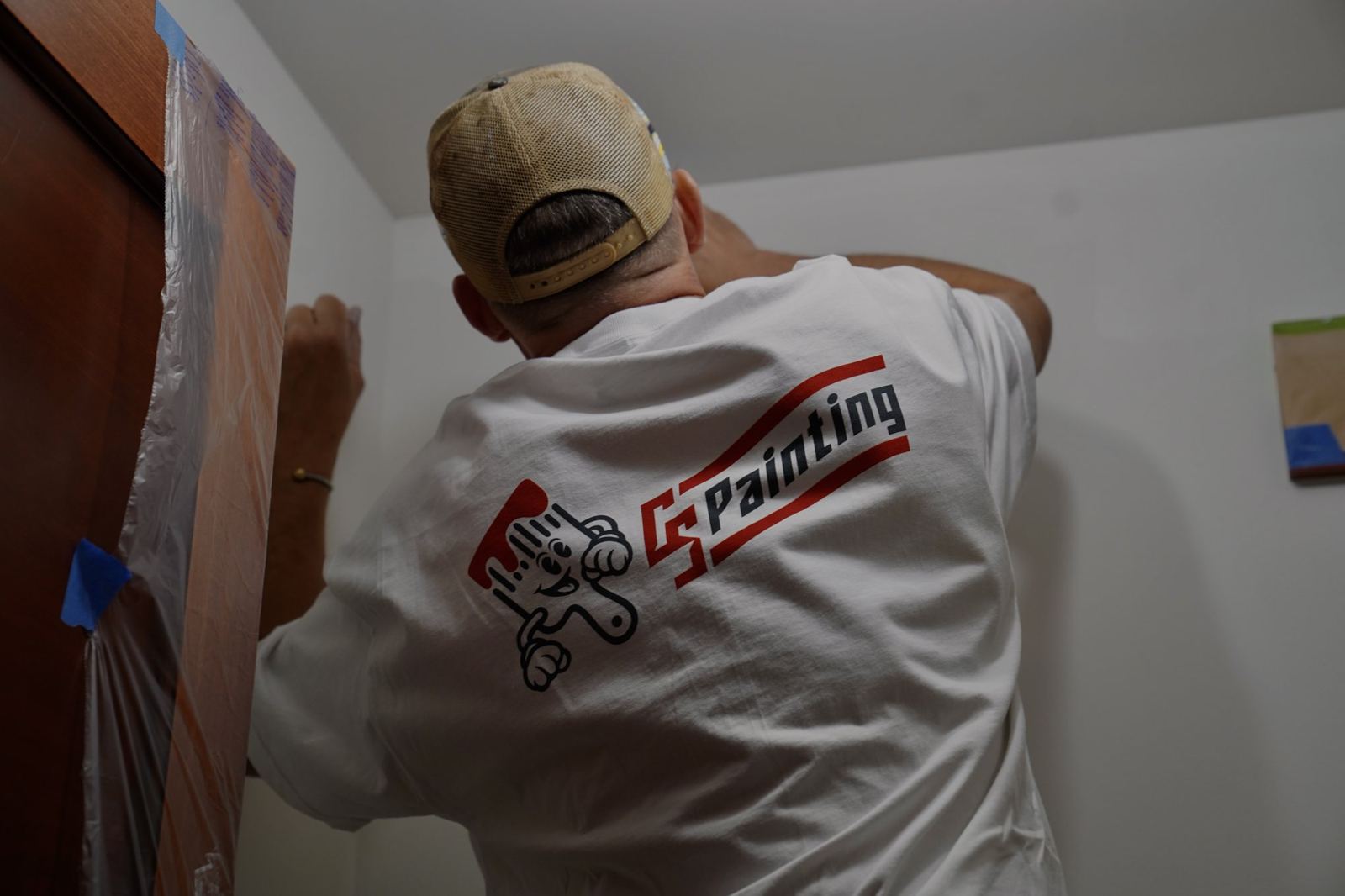 A CS Painting crew member taping off a wall before painting